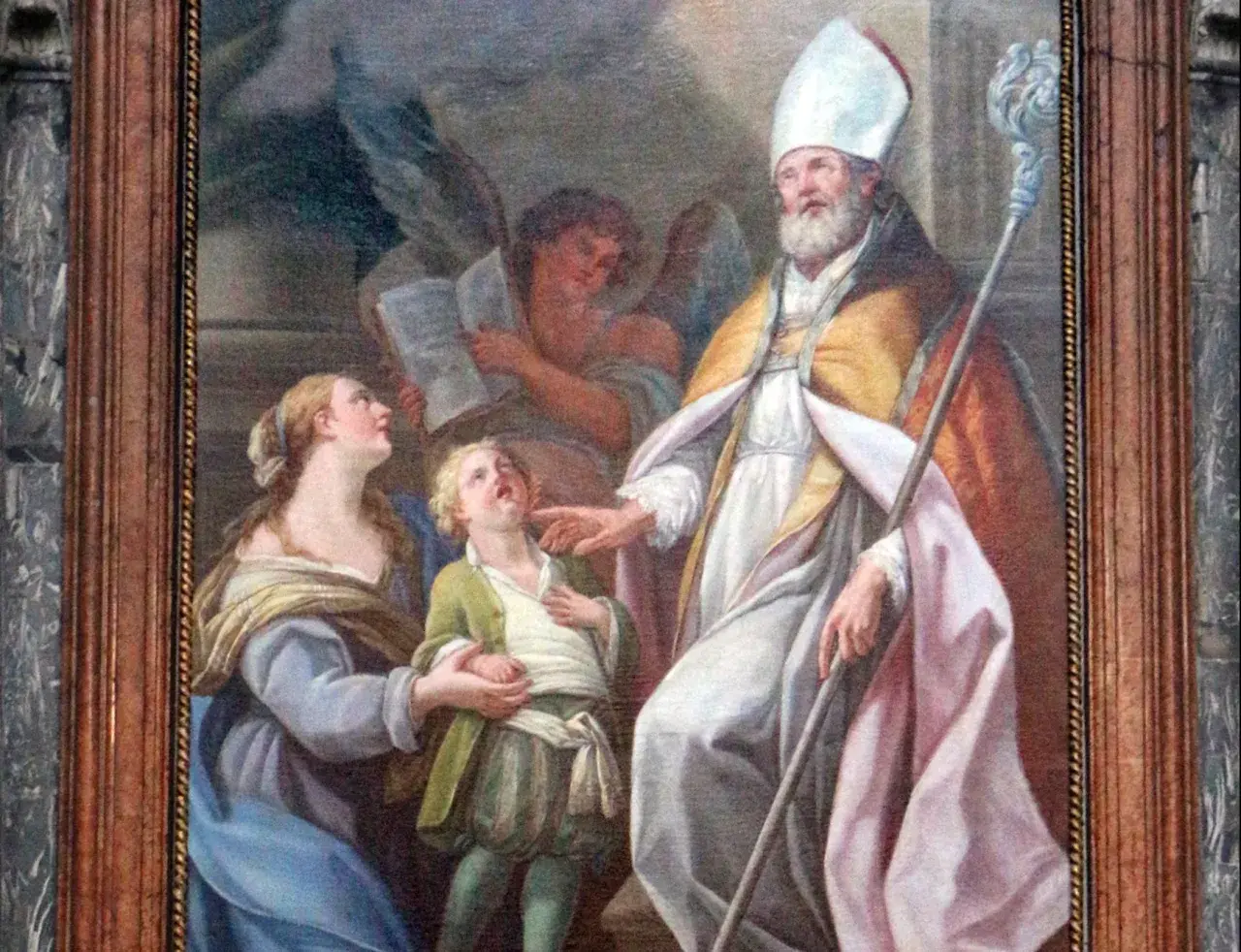 San Biagio, con mitra e pastorale, benedice un bambino. Il nome Biagio evoca protezione e guarigione.
