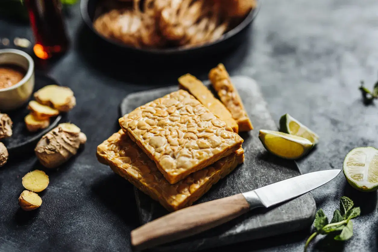 Pezzi di tempeh in agrodolce pronti per essere cucinati, con zenzero, lime e menta.