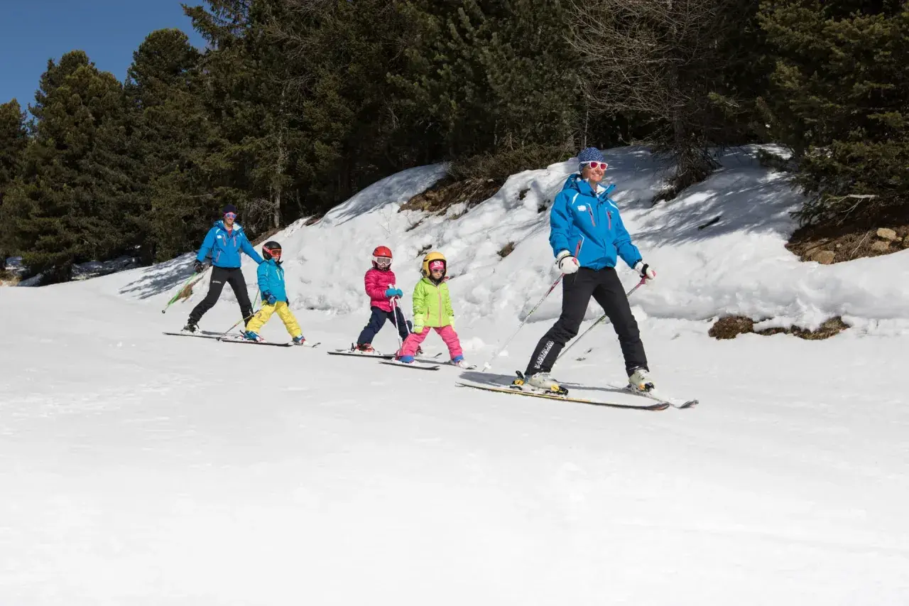 Maestro di sci guida bambini su piste innevate, un'ottima idea per dove sciare con bambini.
