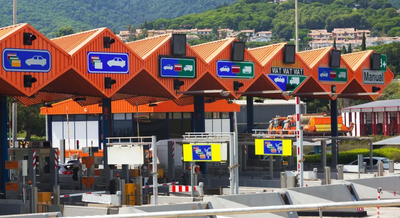 Carriles de peaje con señales que indican cómo pagar. Hay señales para coches y camiones, y una para pago manual.