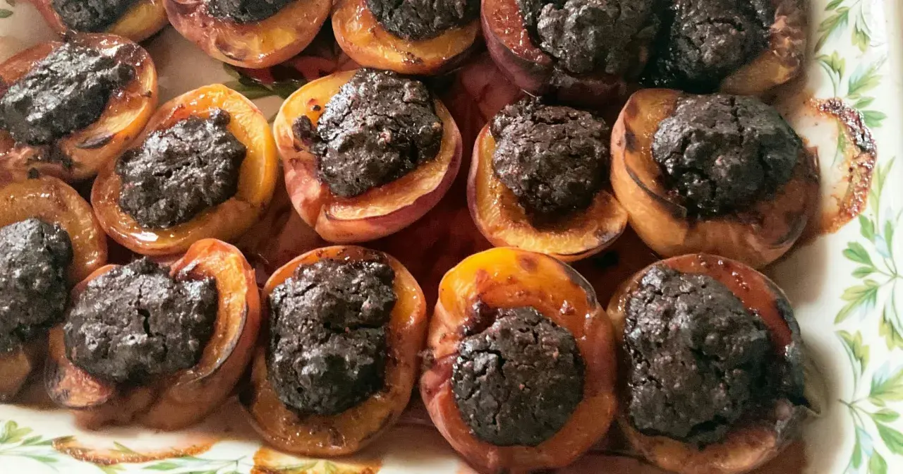 Deliziose pesche ripiene al forno, con un ripieno scuro e invitante, pronte per essere gustate.