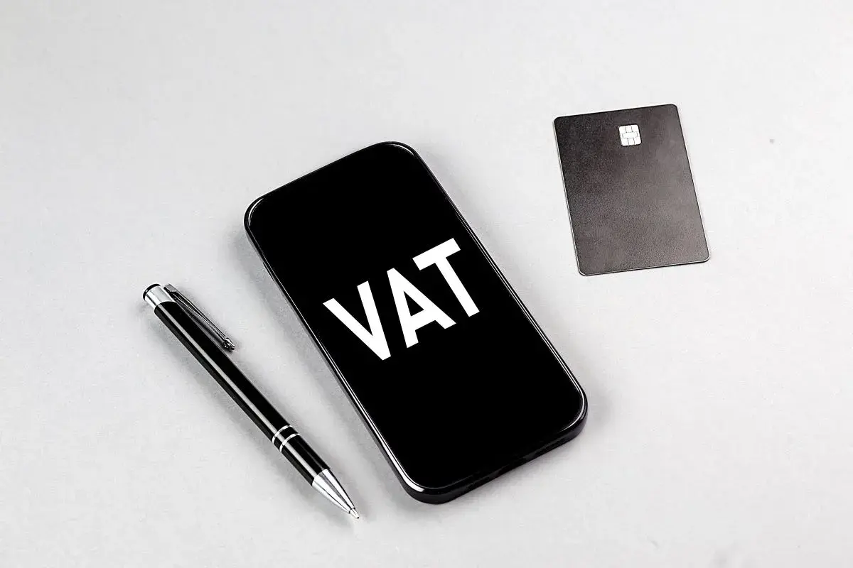 Telefon z napisem VAT, obok długopis i karta płatnicza. Ułatwia to ptu rejestracja.
