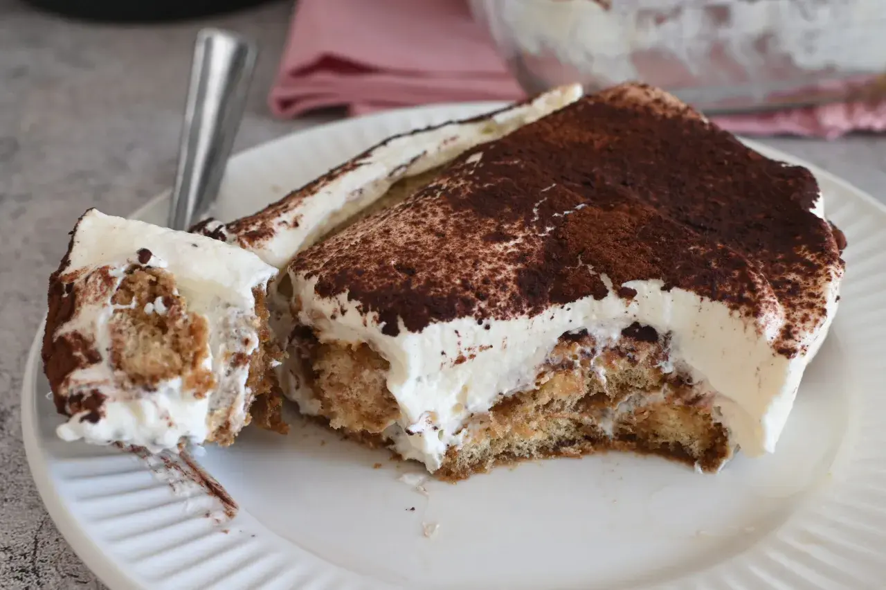Fetta di tiramisù con abbondante crema al mascarpone 500 g, cosparsa di cacao amaro.