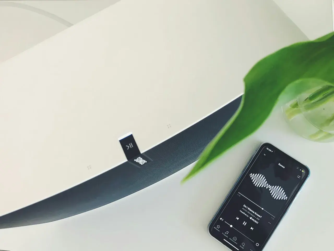 Telefon z aplikacją Sonos i odtwarzaną muzyką, obok głośnik tej marki. To pokazuje, jak działa airplay co to za technologia.