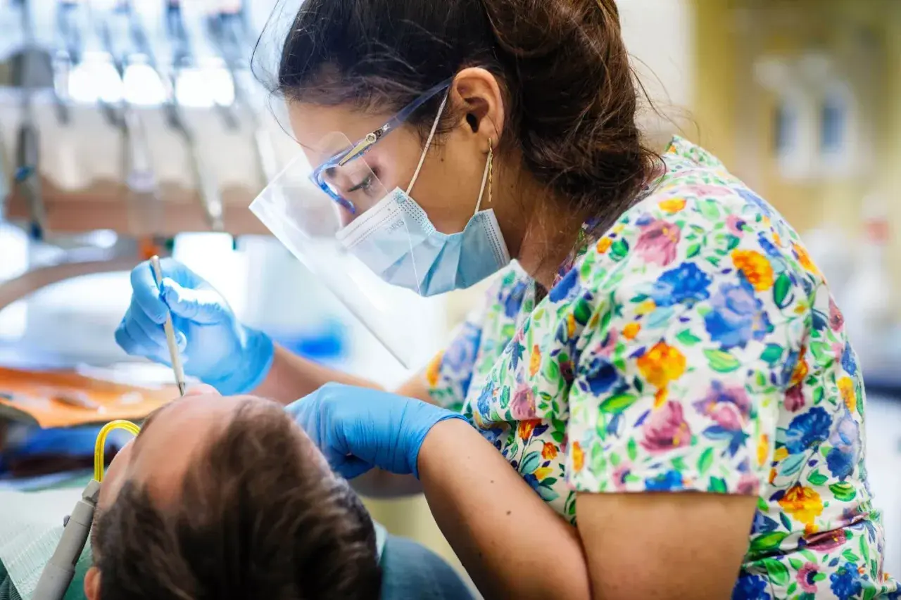 Dentystka w maseczce i okularach ochronnych wykonuje zabieg podniesienia dna zatoki szczękowej.