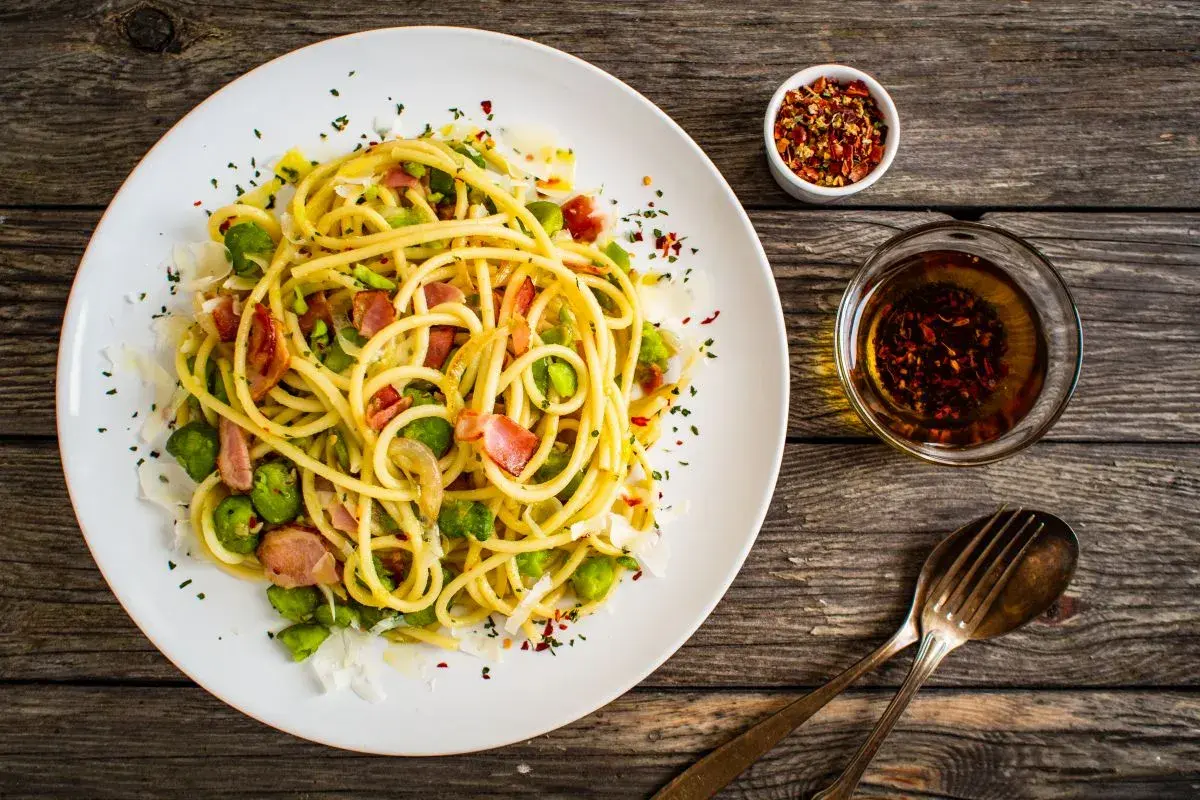 Pyszny makaron z bobem, chrupiącym boczkiem i parmezanem, podany z oliwą i płatkami chili. Idealny na szybki obiad.