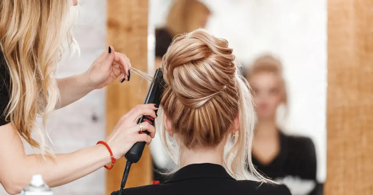 Fryzjerka stylizuje eleganckie upięcie. Zastanawiasz się, ile zarabia fryzjer? To zależy od wielu czynników, ale umiejętności i doświadczenie są kluczowe.