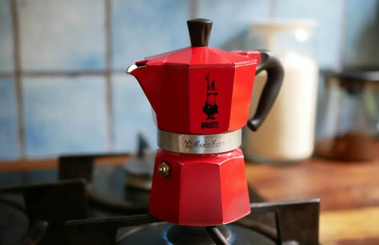 Czerwona kawiarka Bialetti Moka Express na kuchence, gotowa do zaparzenia aromatycznej kawy. To klasyczny sposób na espresso w domu.