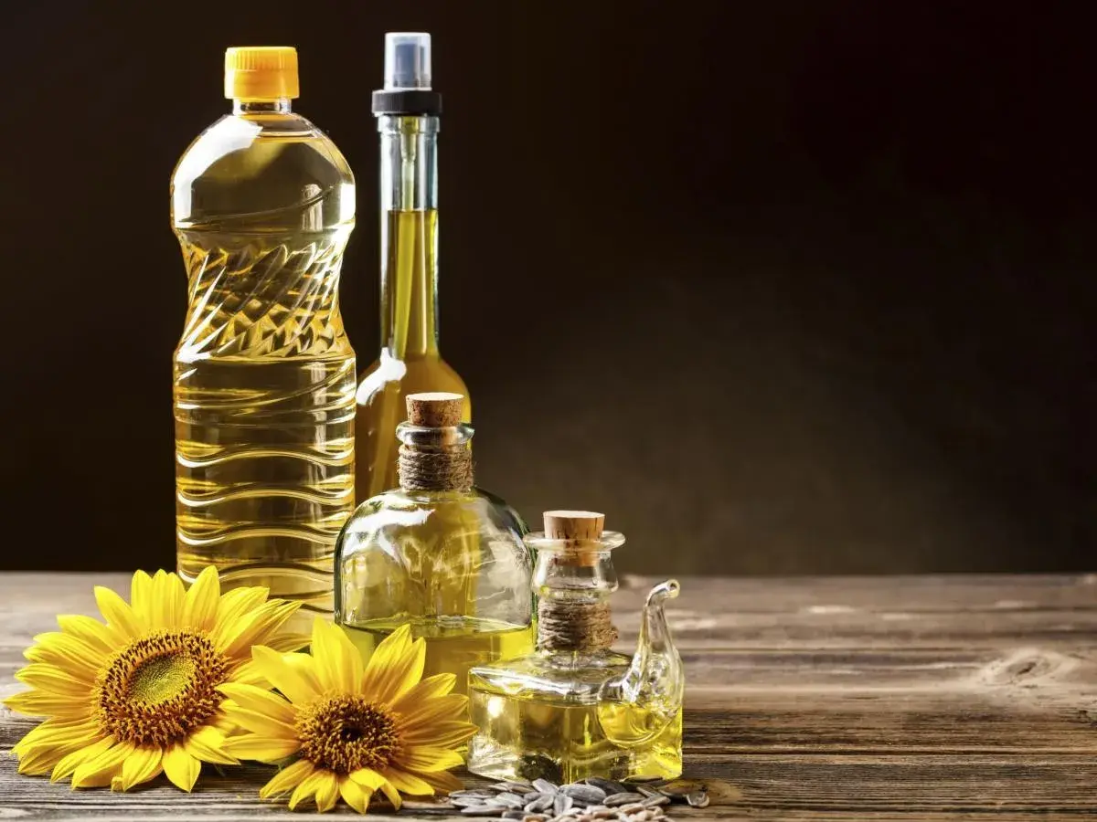 Bottiglie di olio di semi e girasoli. Si può mischiare l'olio d'oliva con l'olio di semi per un sapore unico.