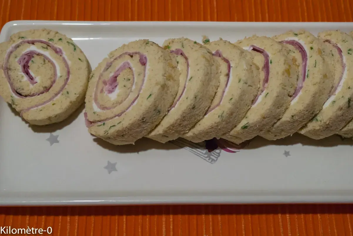 Un roulé au jambon fromage, coupé en tranches, garni de fromage frais et de fines herbes. Parfait pour un apéritif.
