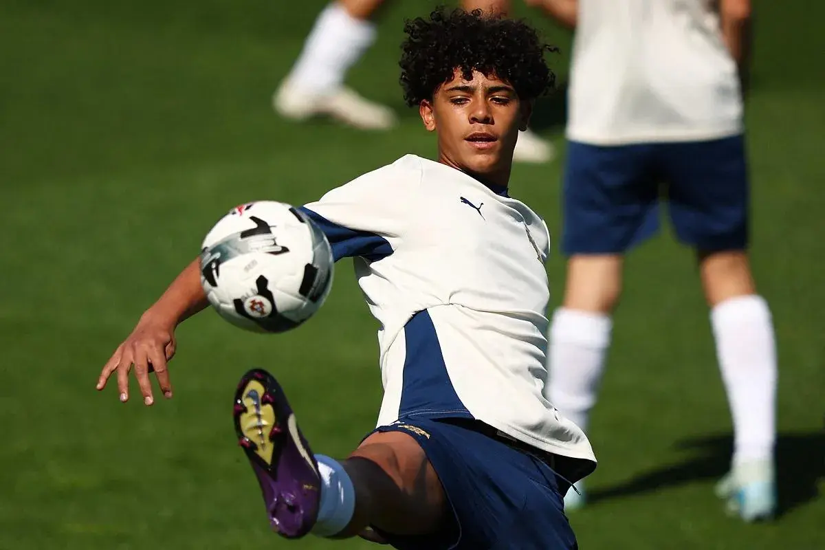 Młody piłkarz, niczym cr7 jr., trenuje na boisku, wykonując efektowne kopnięcie.
