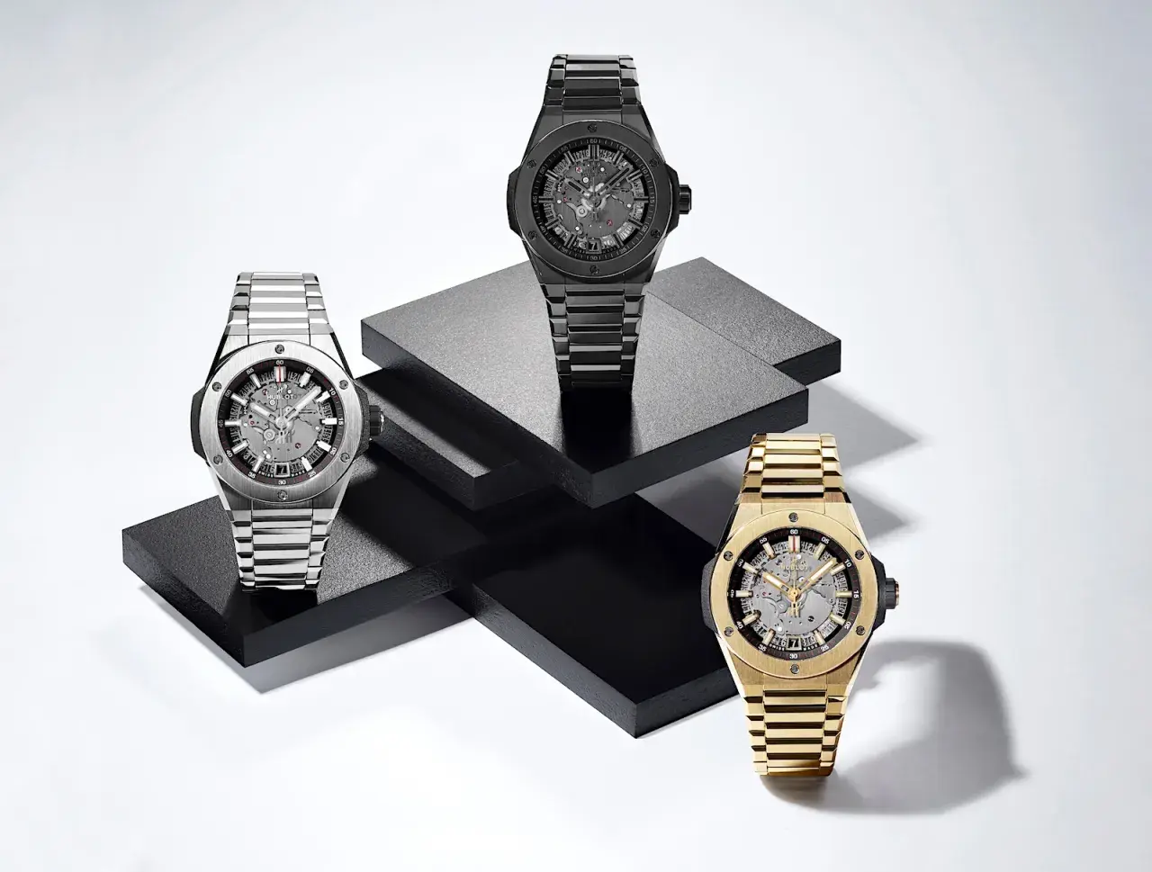 Tres relojes de lujo, uno plateado, uno negro y uno dorado, exhiben la elegancia del **Big Bang reloj**.
