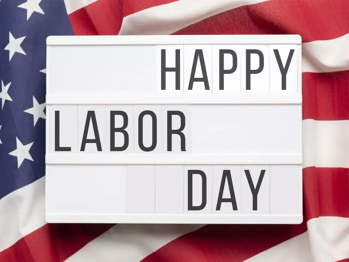 Cartel luminoso con "HAPPY LABOR DAY" sobre bandera de EE.UU. Celebrando el día del trabajador en inglés.