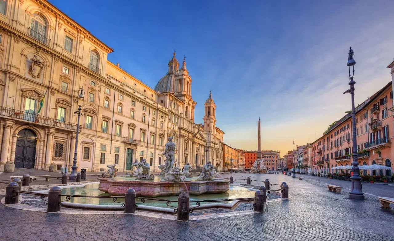 Fontana dei Quattro Fiumi e il palazzo prospiciente in Piazza Navona, Roma, al tramonto.