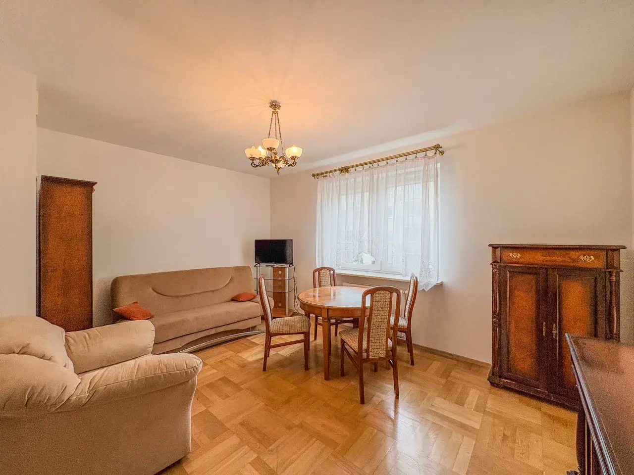 Przytulny salon z kanapą, fotelem i stołem z krzesłami. Klasyczne meble tworzą atmosferę domowego ciepła w tym aurec home.