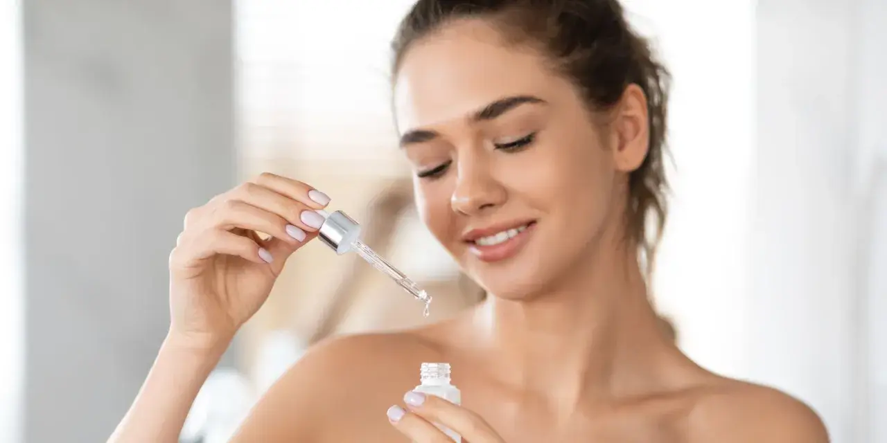 Une femme applique un sérum à la vitamine A rétinol pour une peau éclatante.
