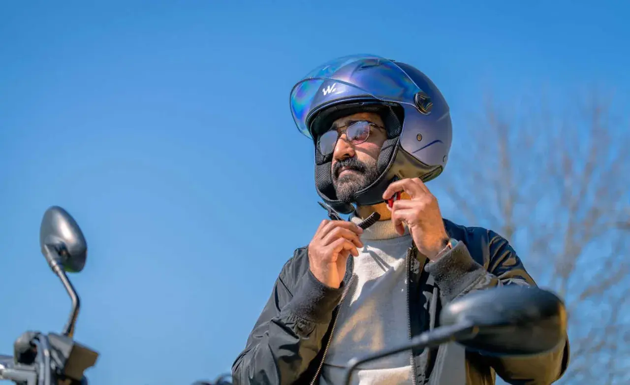 Uomo con casco blu metallizzato, pronto per un giro in moto. Il casco taglia 58 a cosa corrisponde? Probabilmente una misura media, perfetta per lui.