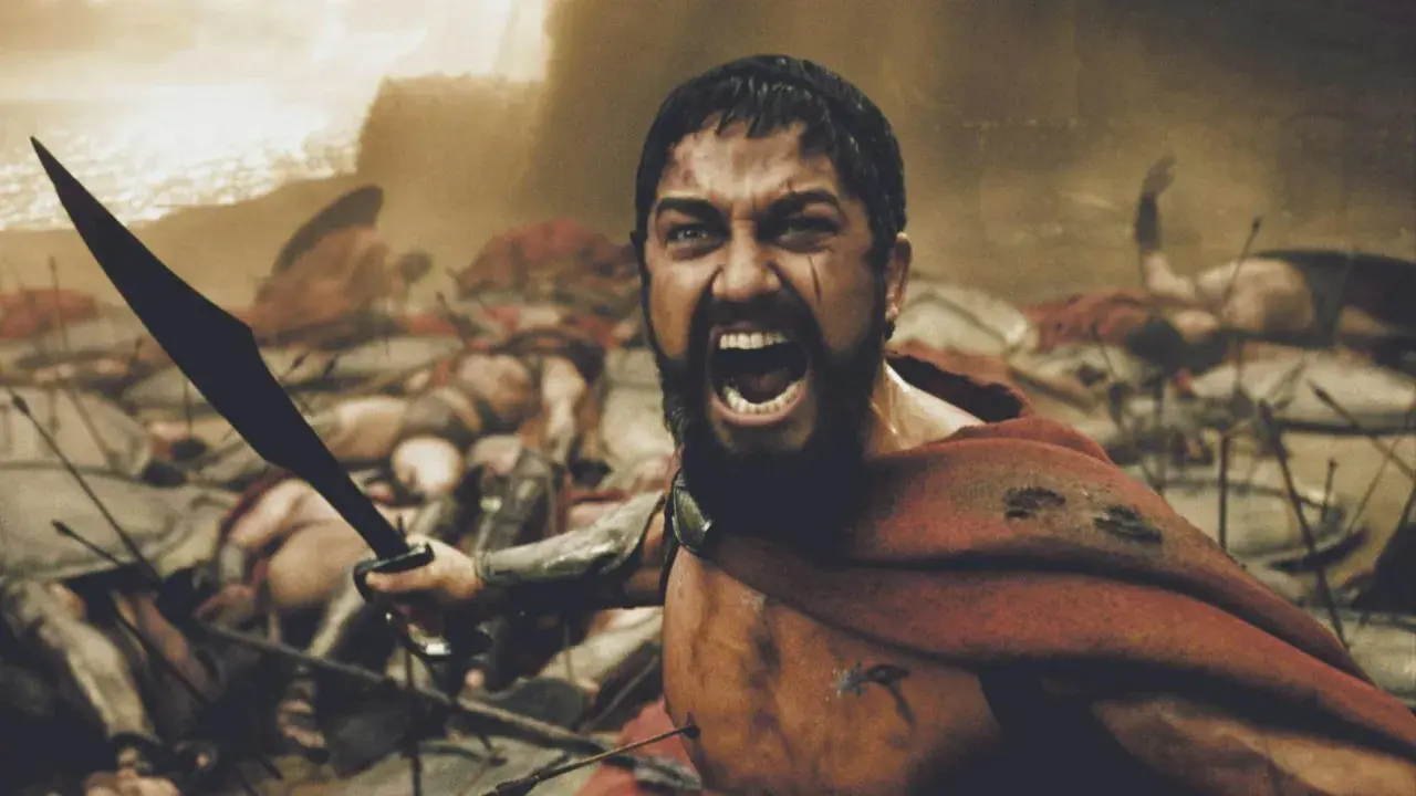 Leonidas, med svärdet höjt, vrålar i strid bland fallna krigare. En ikonisk scen från rollistan i 300.