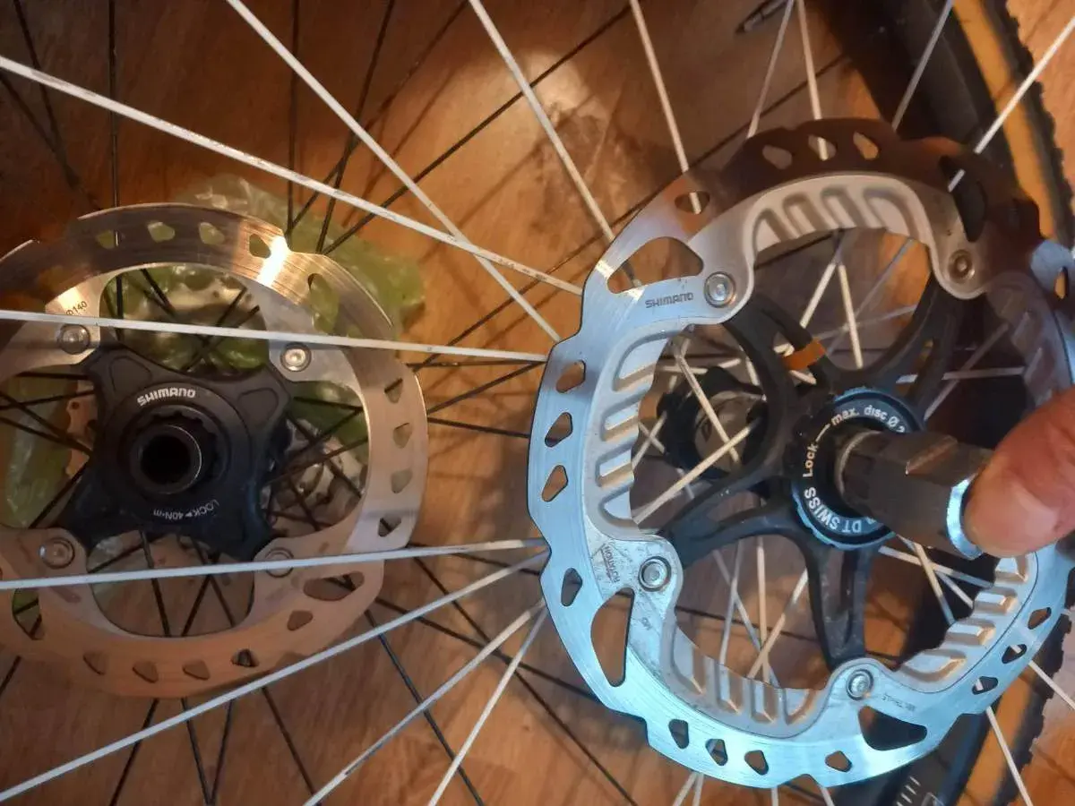 Dwa hamulce tarczowe rowerowe, jeden z mocowaniem center lock Shimano, drugi z mocowaniem center lock DT Swiss.