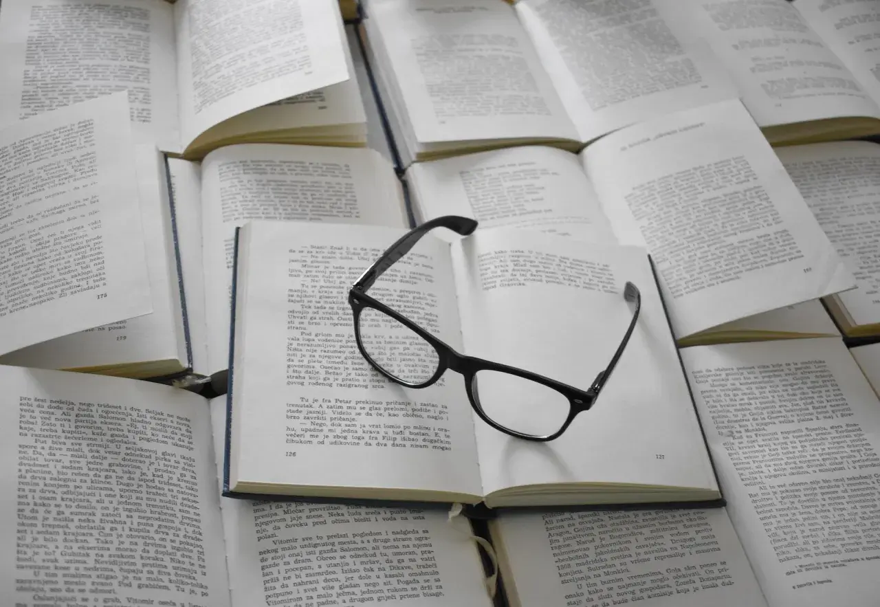Lunettes posées sur des livres ouverts. Ces figures de style servent à enrichir le texte et à rendre la lecture plus captivante.