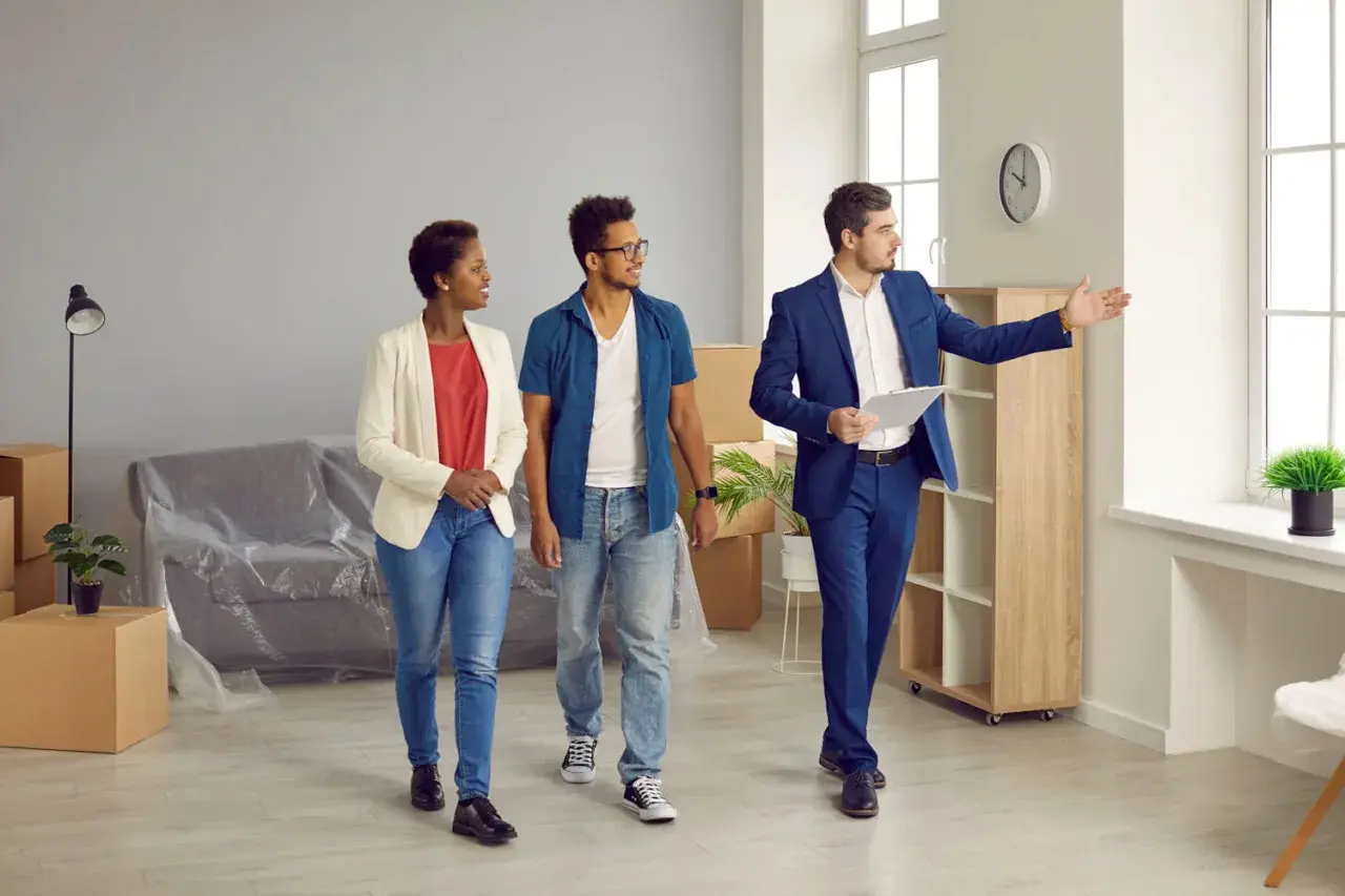 Un agent immobilier présente un appartement à un couple. Ils consultent leur checklist visite appartement.