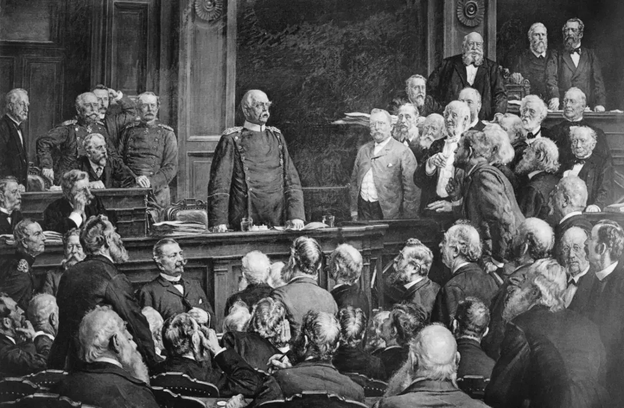 Bismarck steht im Mittelpunkt einer Versammlung, die den Berliner Vertrag darstellt. Männer in Anzügen und Uniformen diskutieren.