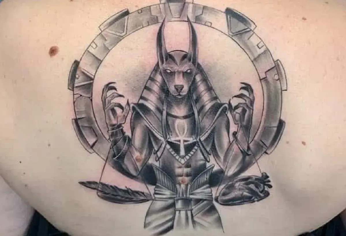 Tatuaje de Anubis con un corazón y pluma, simbolizando el juicio y el significado de la vida.