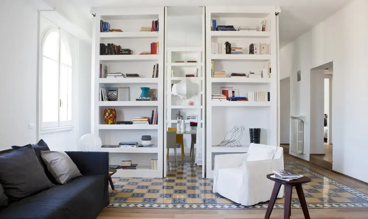 Parete divisoria in cartongesso con librerie bianche e nicchie decorative.