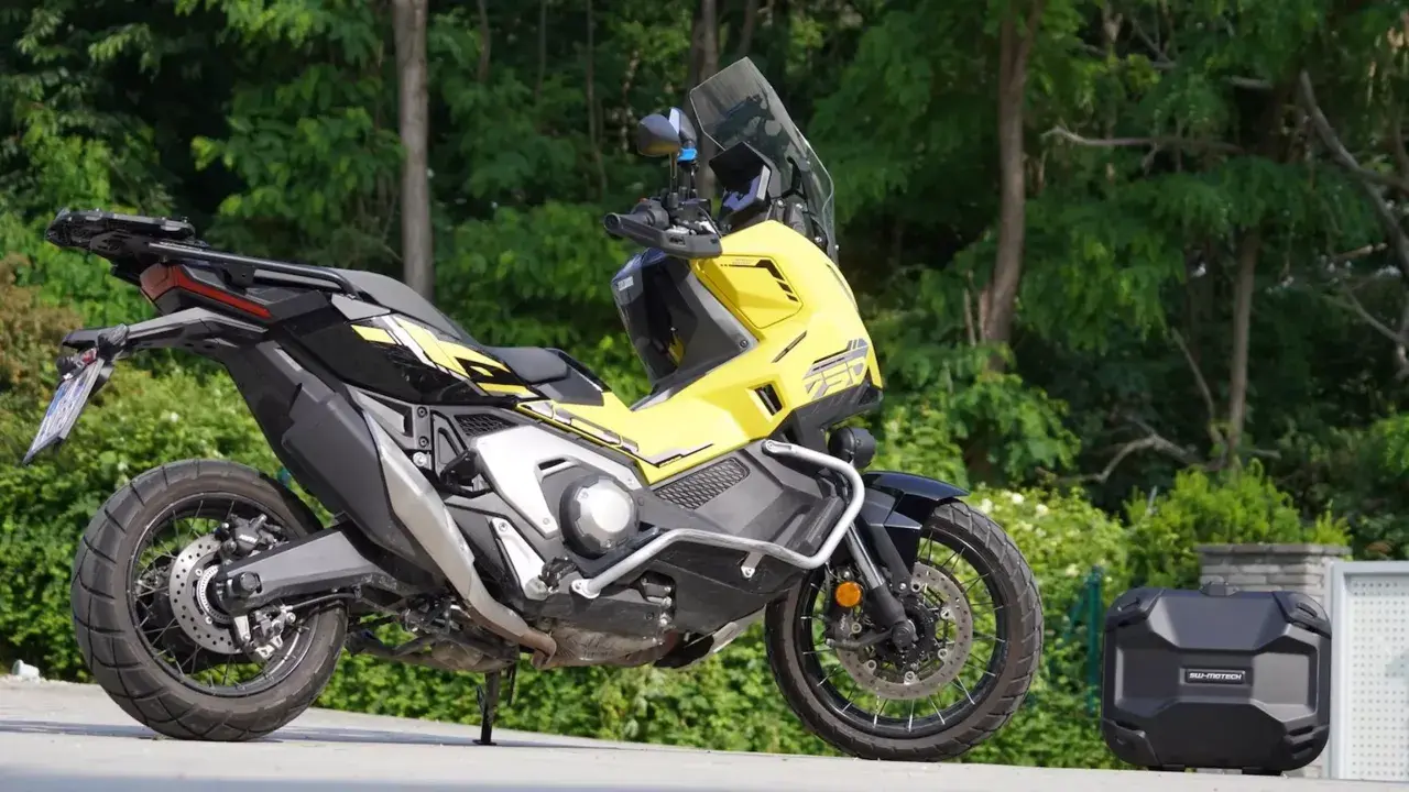 Żółty Honda X-ADV 750 z czarnymi akcentami, gotowy na przygodę. Obok bagażnik kufer.