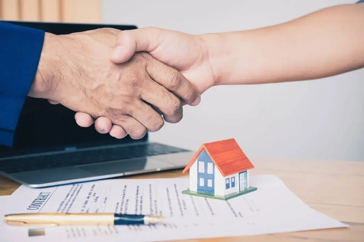 Poignée de main sur un contrat immobilier, symbolisant un accord respectant la loi du 6 juillet 1989 sur les réparations locatives.