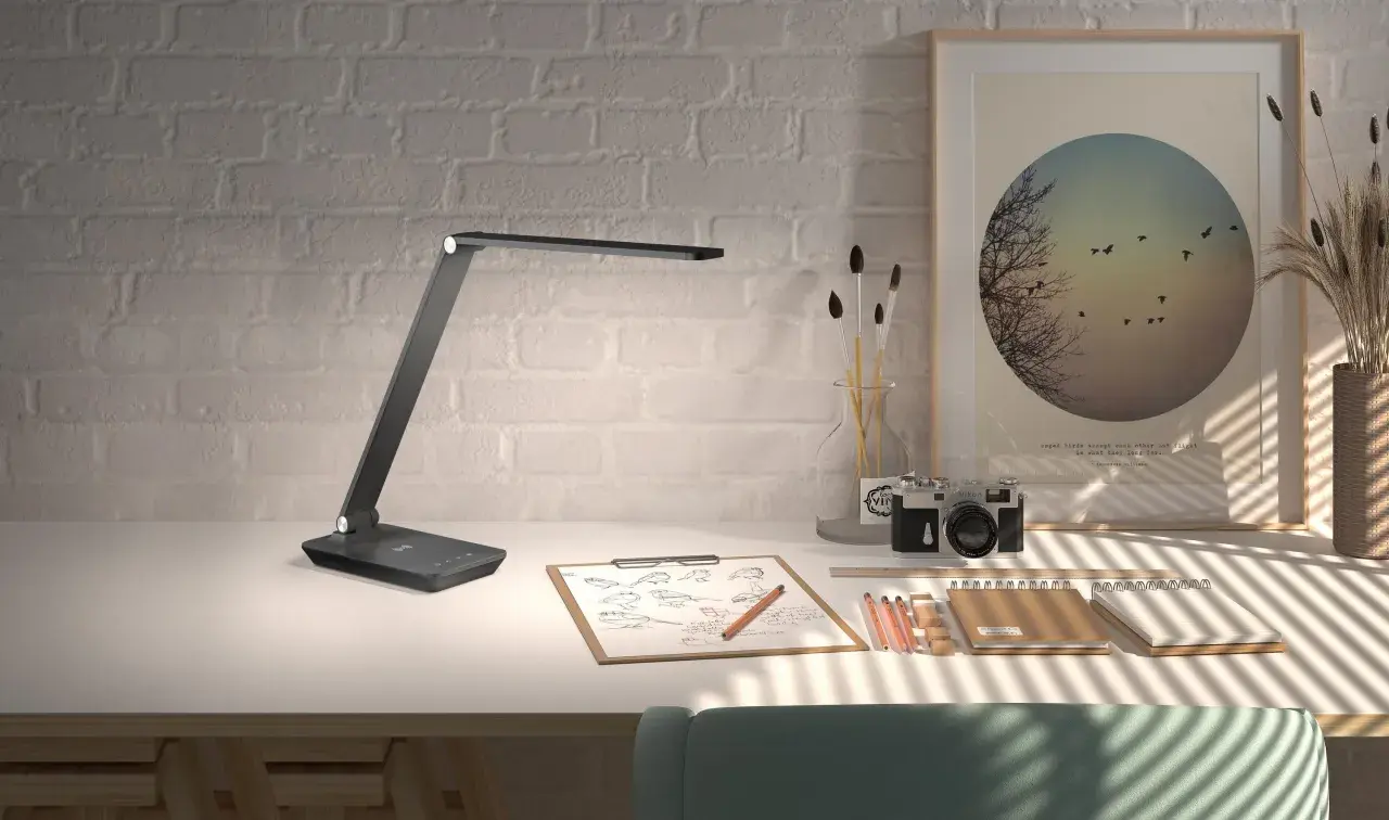 Flexo LED USB moderno sobre escritorio con cámara antigua, bocetos y arte.