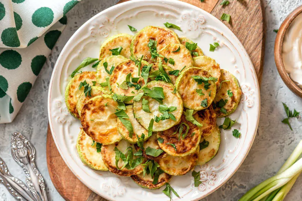 Fette di zucchine dorate e profumate, un'idea per una ricetta zucchine light veloci e gustosa, guarnite con prezzemolo fresco.