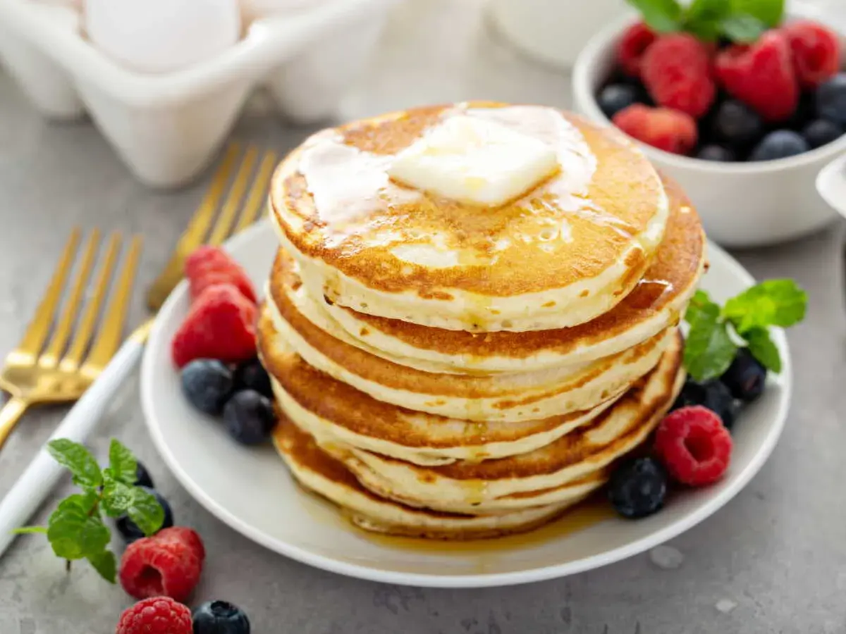 Pile de pancakes sans oeuf, dorés et moelleux, garnis de beurre fondant et de fruits rouges frais. Un délice pour le petit-déjeuner !