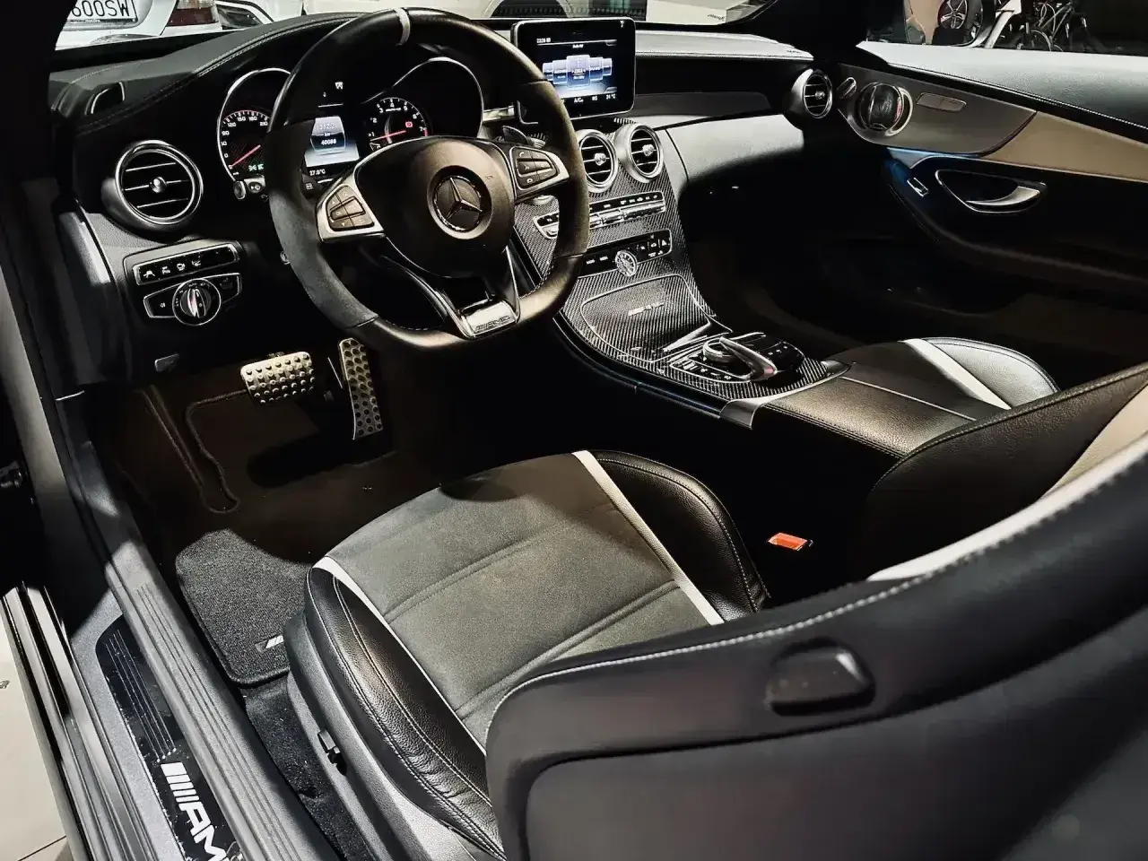 Wnętrze sportowego Mercedesa z kierownicą AMG, karbonowymi wstawkami i siedzeniami. Czekam na jazdę tym v8!