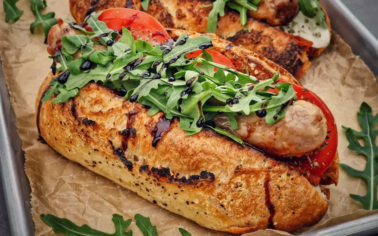 Ein knuspriges Baguette mit einer herzhaften salsiccia italiana, frischen Tomaten und Rucola, beträufelt mit Balsamico.