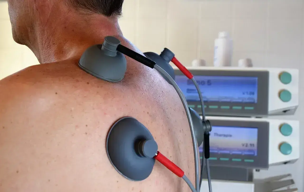 Elektrody TENS na plecach pacjenta. Choć zabieg jest bezpieczny, warto znać potencjalne prądy TENS skutki uboczne.