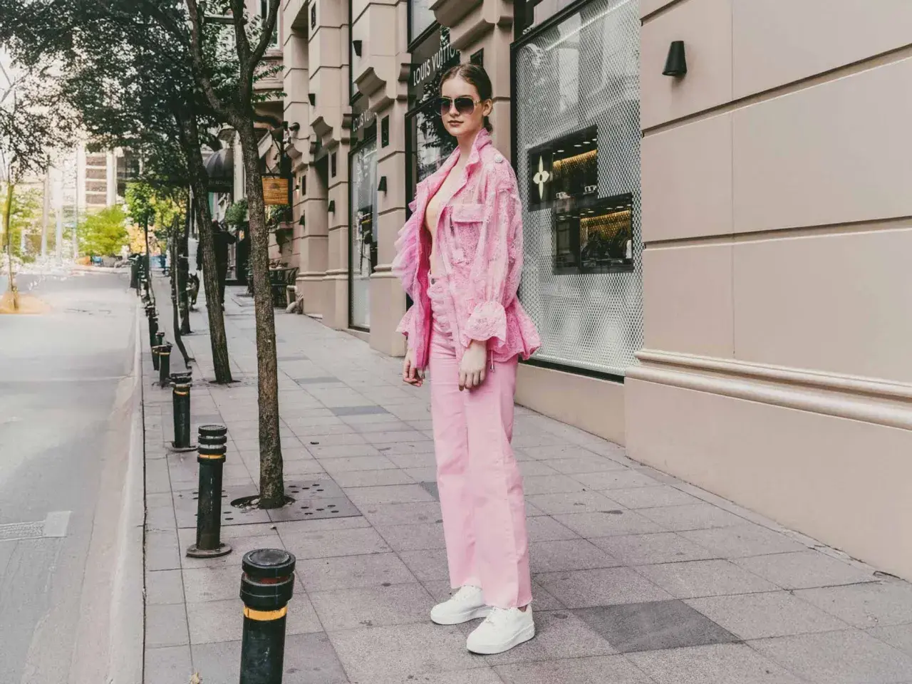 Ein Model präsentiert, wie man **pinke Hose kombinieren** kann: mit einem passenden pinken Spitzen-Blazer und weißen Sneakern.