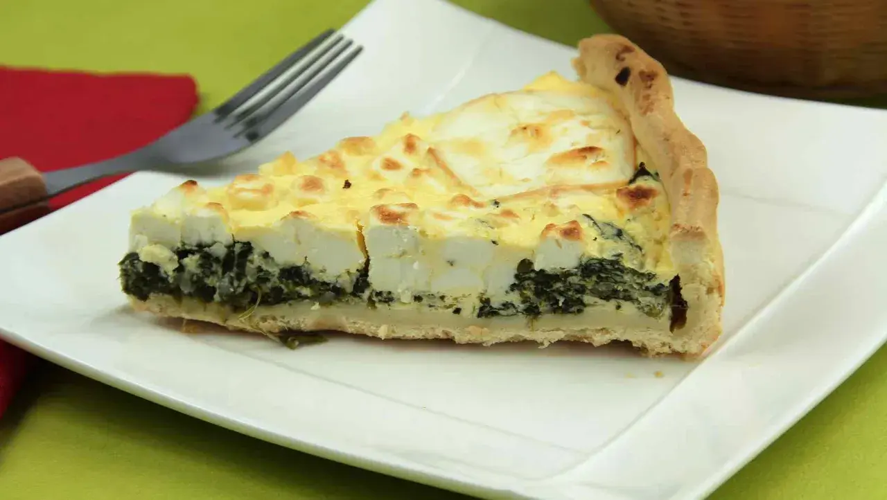 Rebanada de quiche de espinacas con queso feta y una corteza dorada, lista para ser disfrutada.