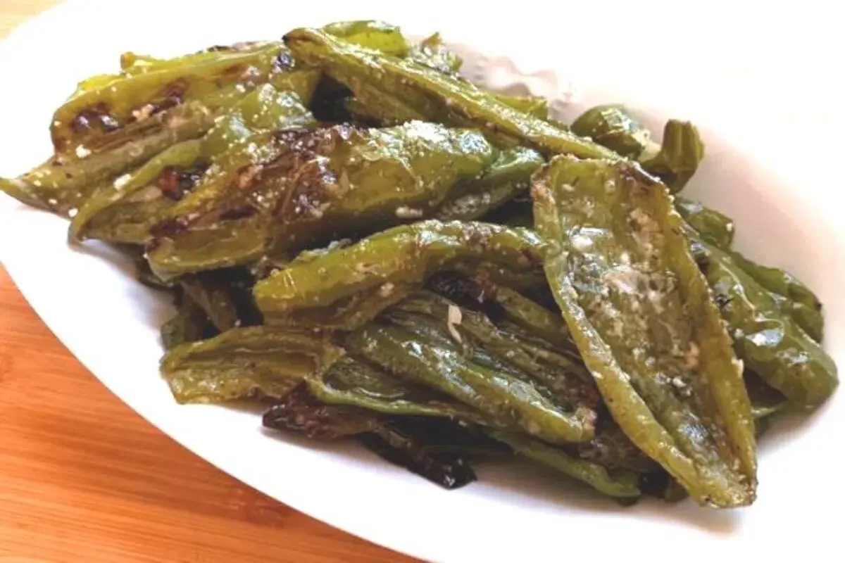 Friggitelli al forno, verdi e lucidi, conditi con sale e spezie, serviti su un piatto bianco.