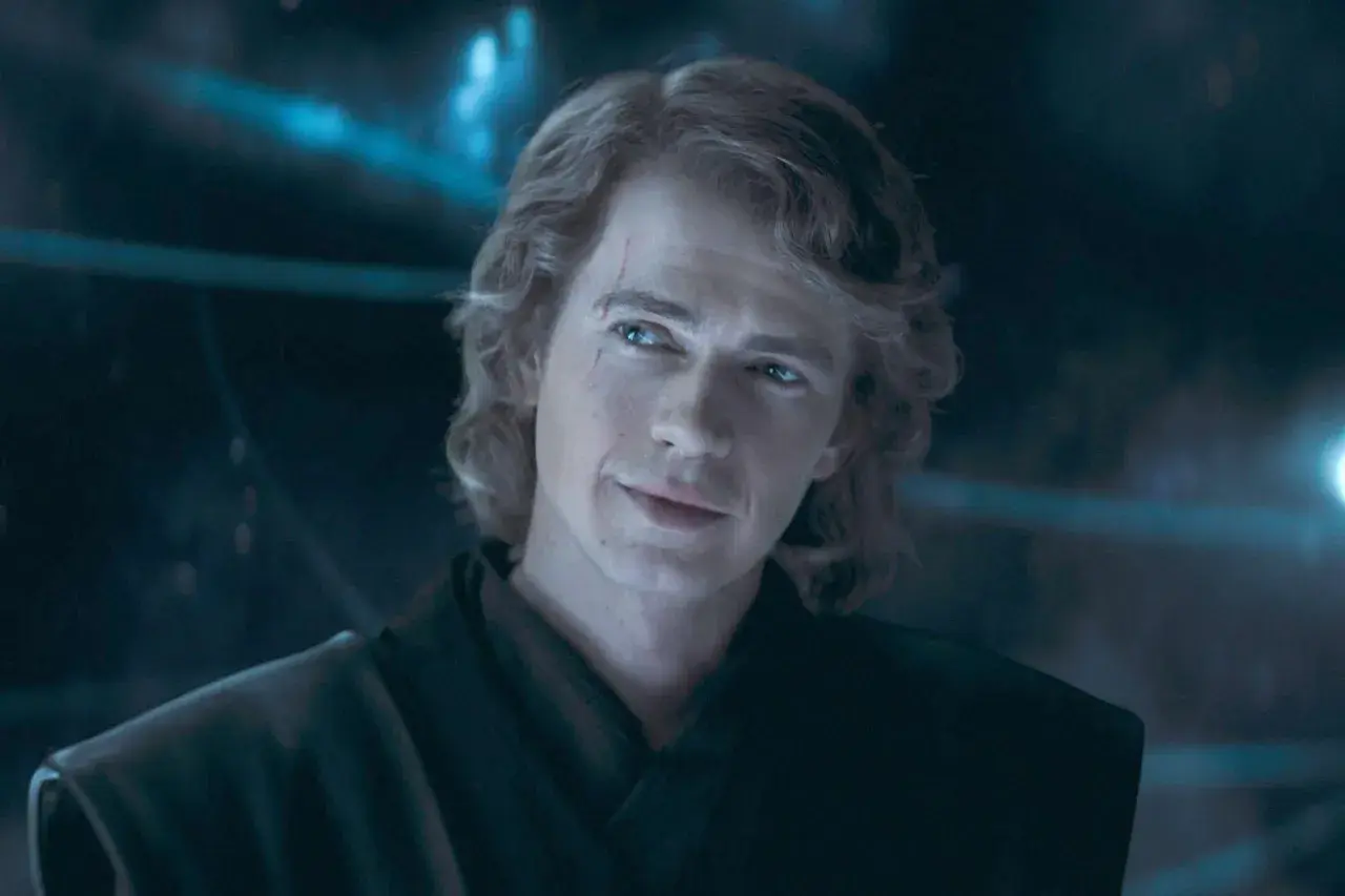 Hayden Christensen som Anakin Skywalker, med ett ärr över ögat och ett snett leende, blickar ut i mörkret.