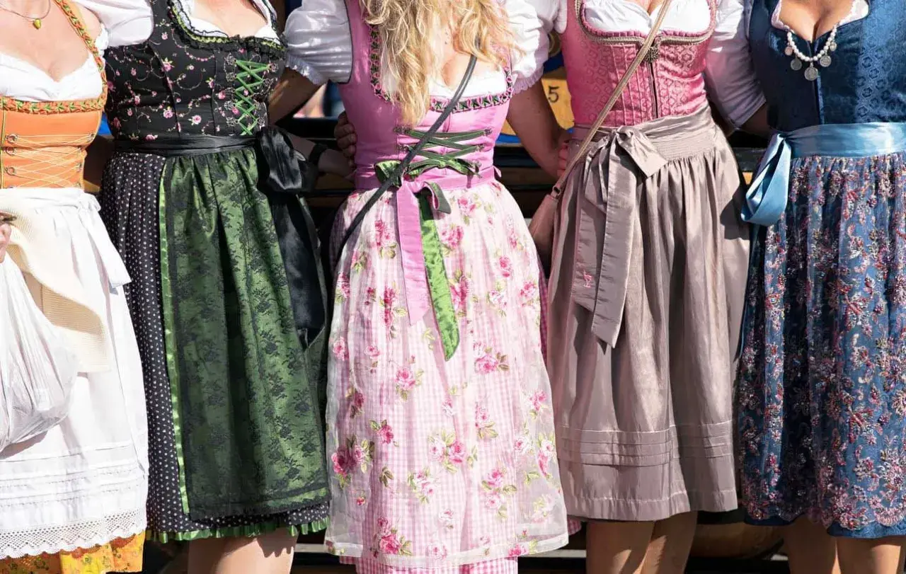 Fünf Frauen in farbenfrohen Chiemgauer Trachten, Dirndl mit Blumenmuster und Spitzenbesatz.