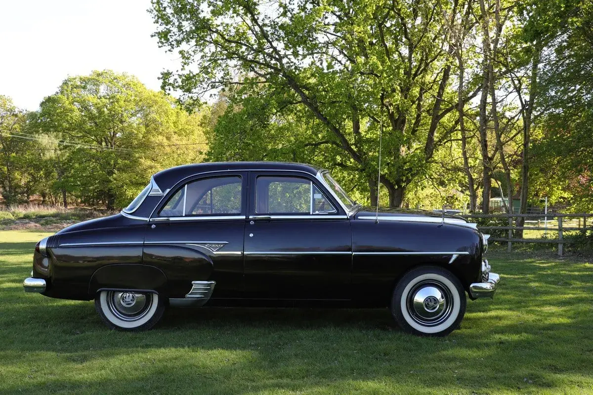 Svart Vauxhall Cresta parkerad på en gräsmatta med träd i bakgrunden.