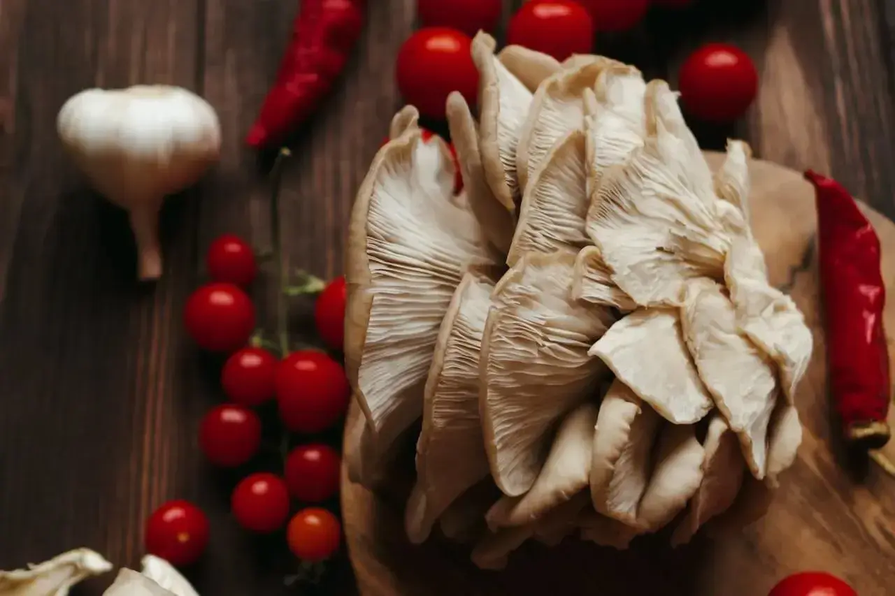 Boczniaki w ciąży, otoczone pomidorkami koktajlowymi, czosnkiem i papryczkami chili, gotowe na kulinarną podróż.