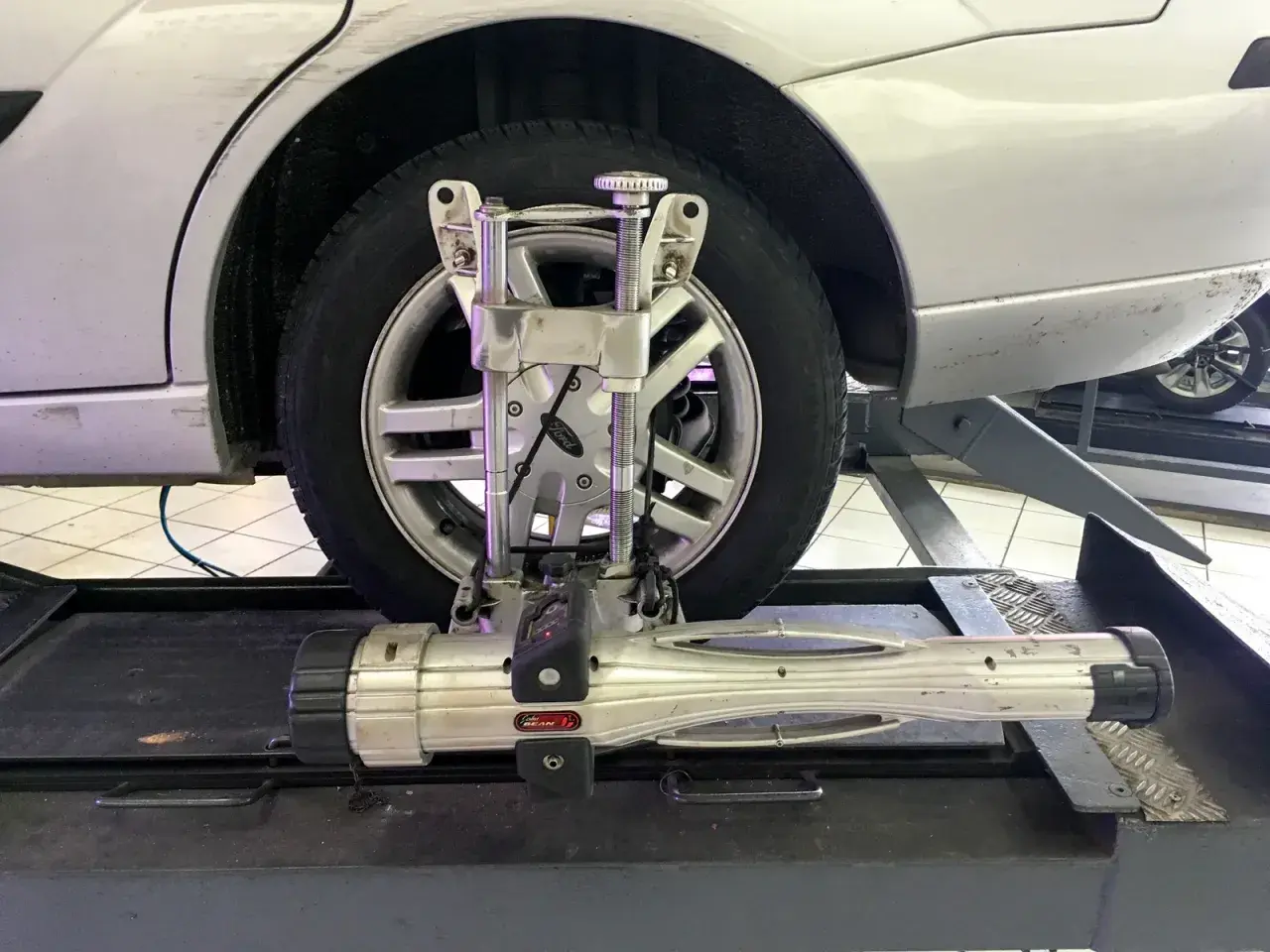 Réglage du parallélisme voiture avec un appareil de mesure sur une roue.