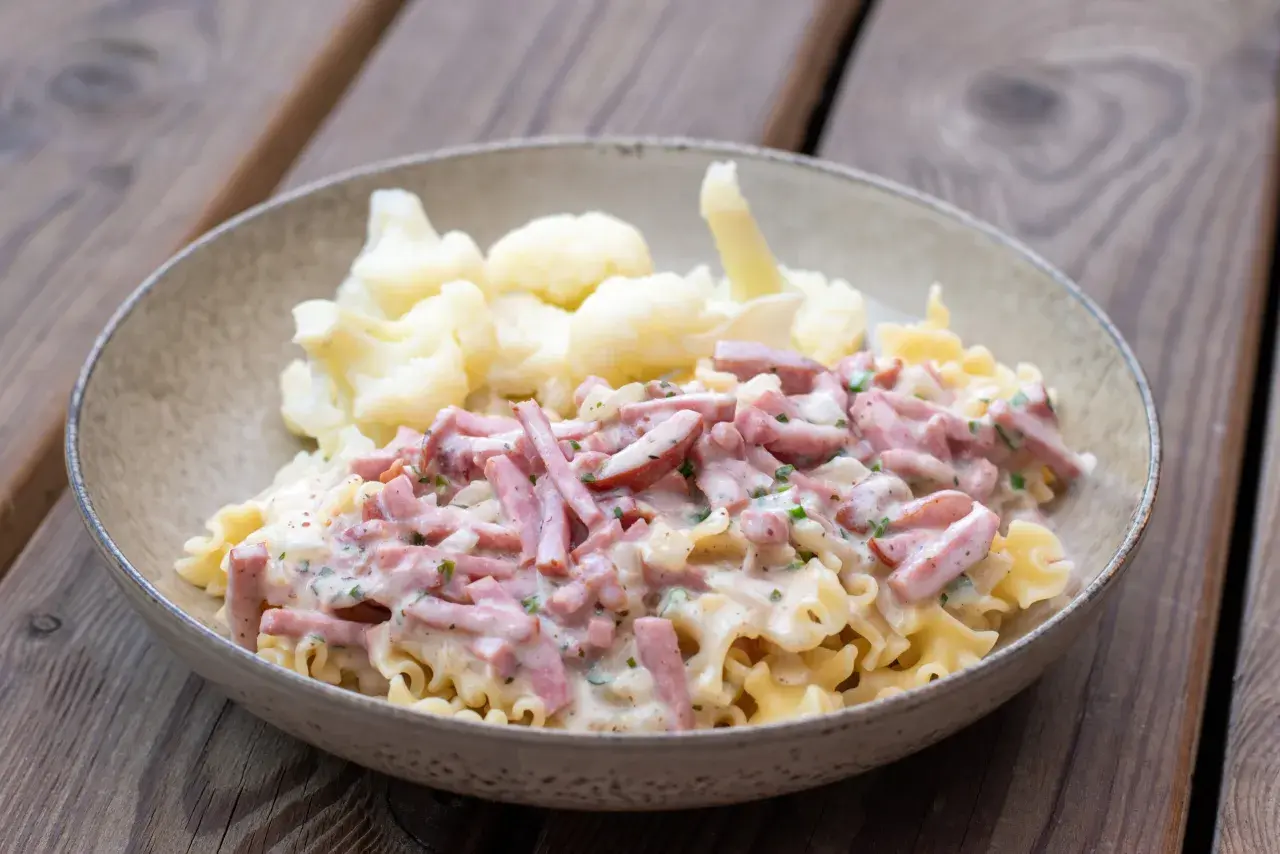 En skål med krusig pasta och skinksås, serverad med blomkål. Enkel och god vardagsmat.