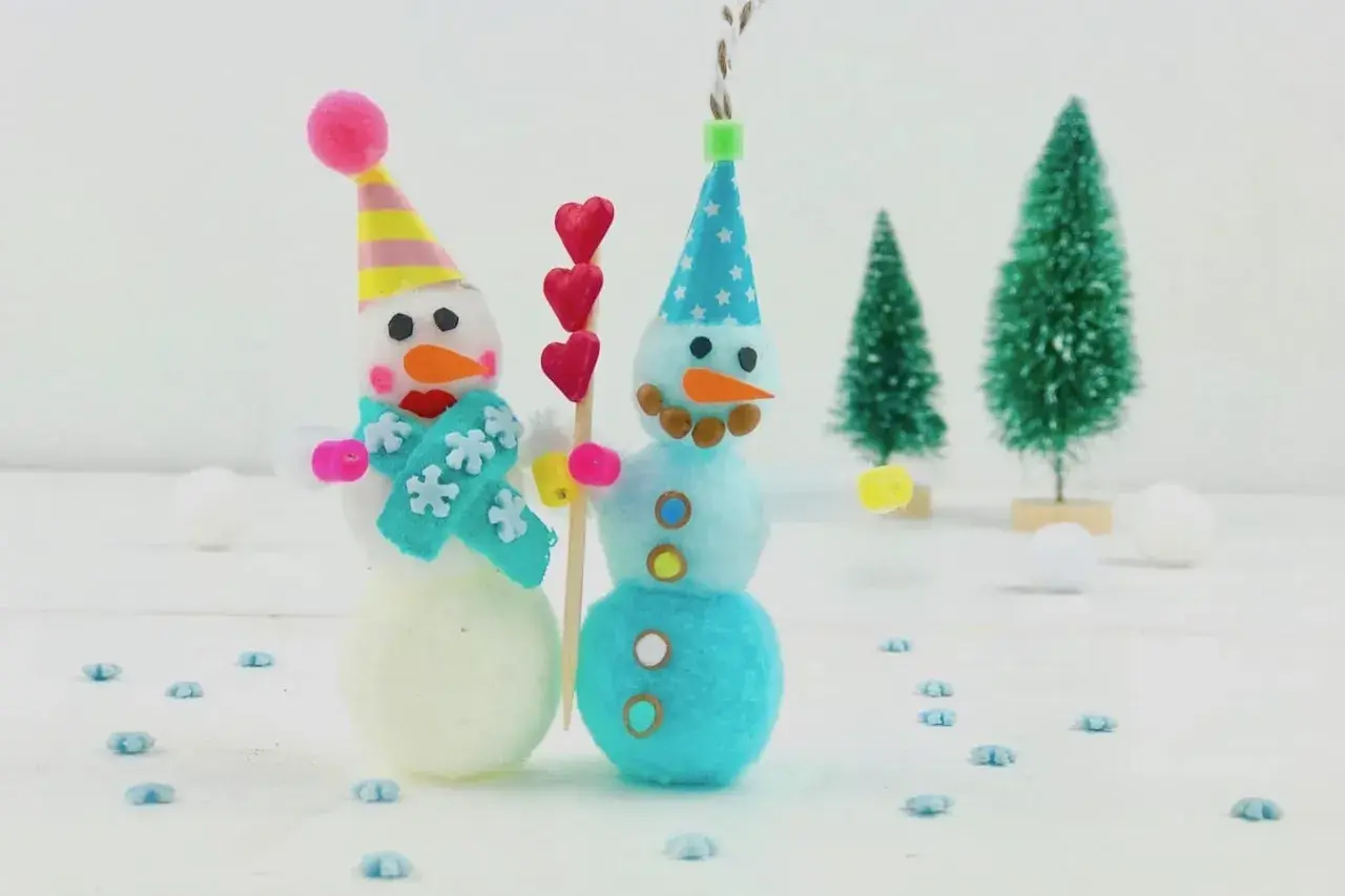 Zwei süße Schneemänner, perfekt zum Basteln Weihnachten Kinder. Sie tragen bunte Mützen und Schals, umgeben von kleinen Weihnachtsbäumen.