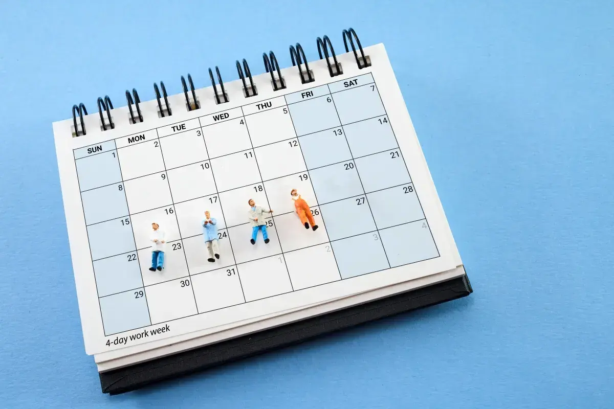 Figurki ludzi na kalendarzu z napisem "4-day work week". Pomaga to zrozumieć, jak wyliczyć średnioroczne zatrudnienie.