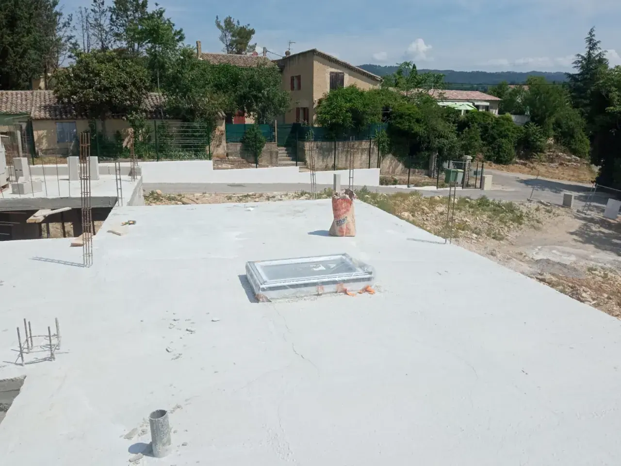 Chantier de construction avec dalle béton fraîchement coulée. Sac de ciment à proximité, peut-être pour estimer le prix dalle béton m2.