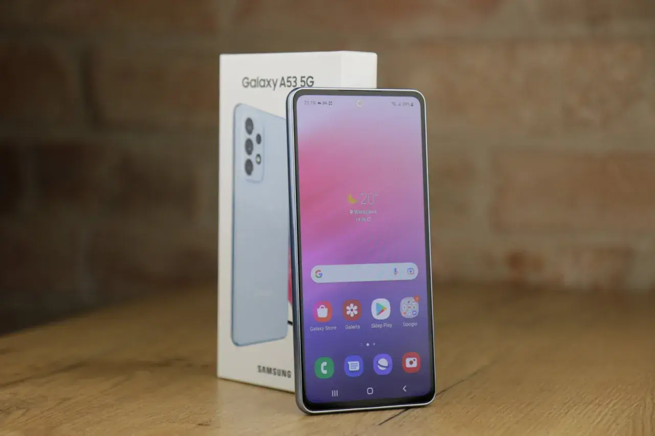 Jasnoniebieski Samsung A53 5G, model z 2022 roku, obok swojego pudełka. Ekran pokazuje pogodę i ikony aplikacji.