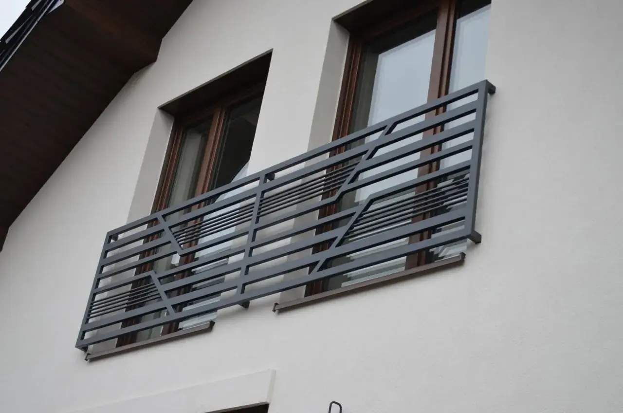 Nowoczesne balkony francuskie z metalową, geometryczną balustradą zdobią elewację domu.